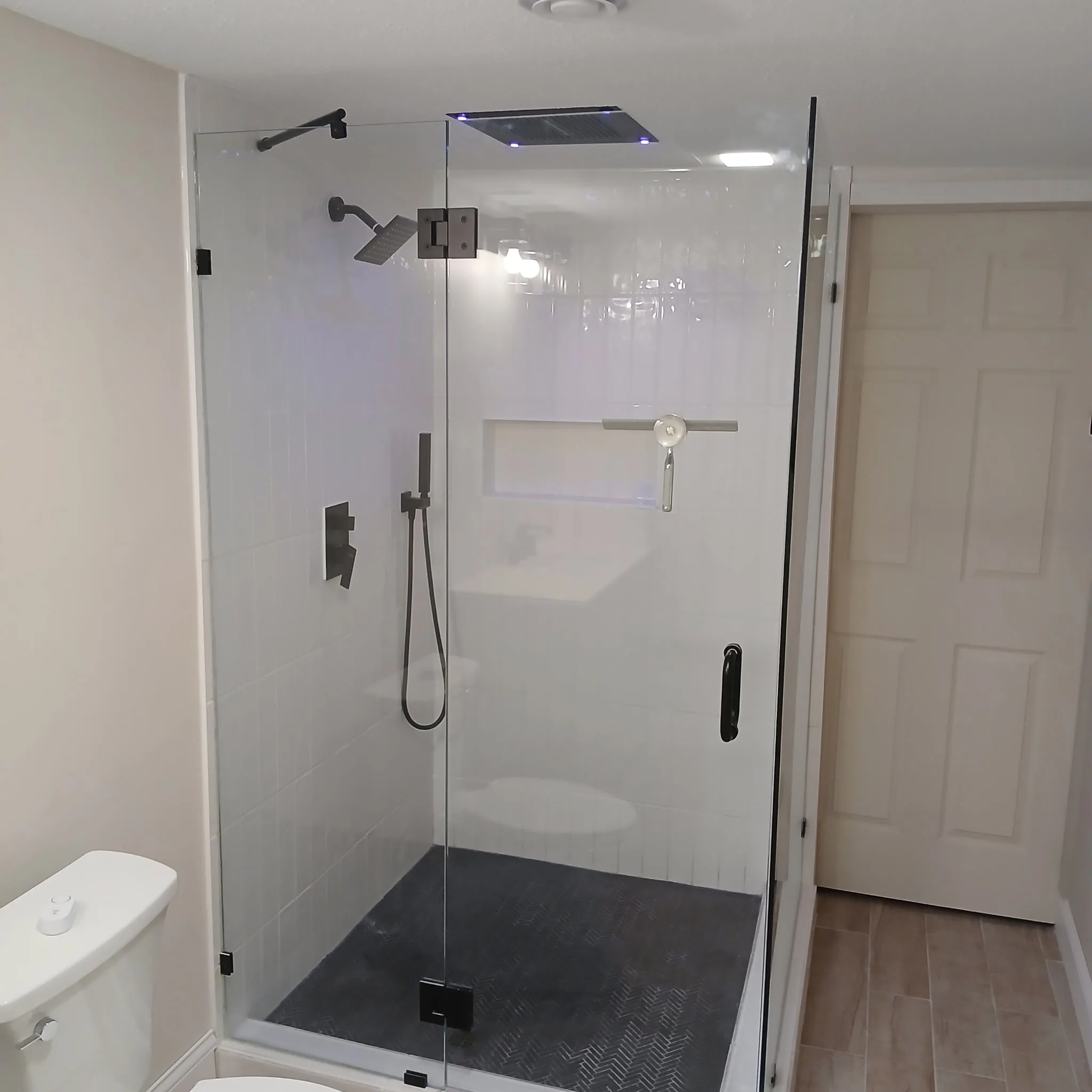 Finished walk-in shower with white tile and glass enclosure